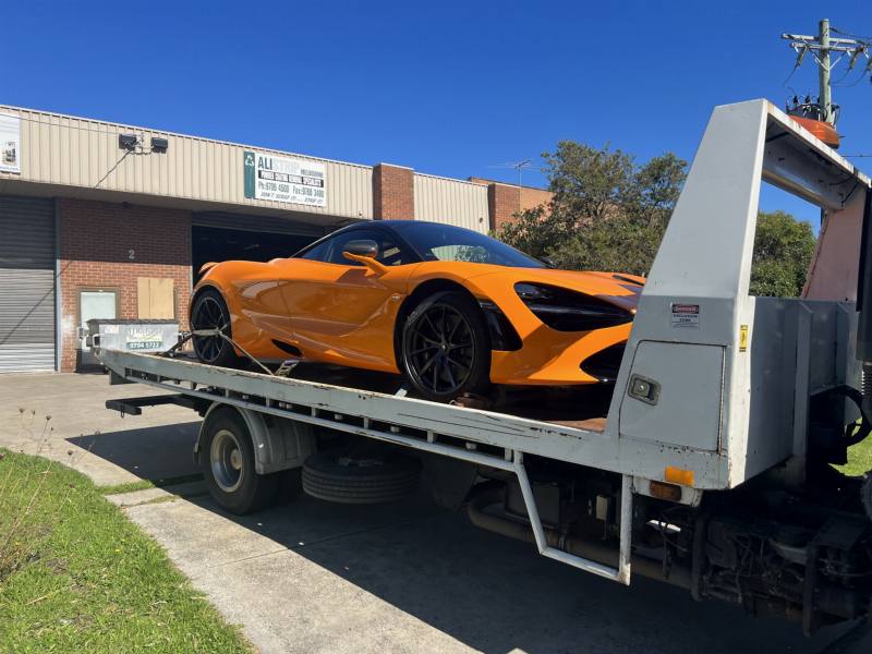 Sports car secured on a tilt-tray truck ready for vehicle transport