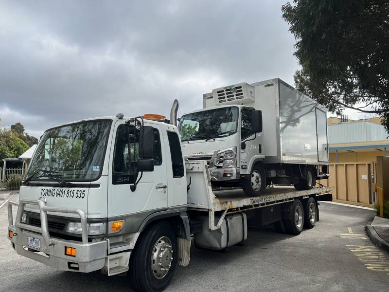 Tow truck with the Hassan phone number carrying a refrigerated light truck